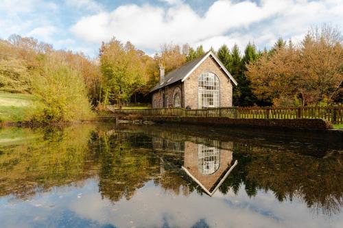 an old church next to a body of water at The Old Pump House in Lydney
