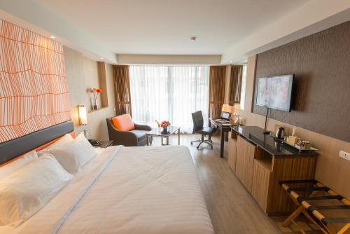 Habitación de hotel con cama grande y escritorio. en Dynasty Grande Hotel, en Bangkok