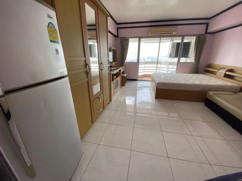 a room with a refrigerator and a bed in it at Mike's Condo in Si Racha