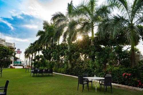 a park with tables and chairs and palm trees at Hotel Chandrawati Palace in Ābu Road