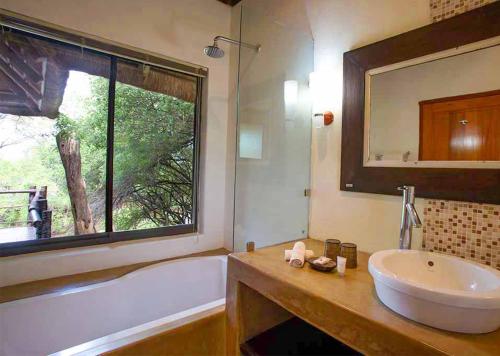 baño con lavabo, bañera y ventana en Madikwe River Lodge by Dream Resorts, en Reserva de Madikwe