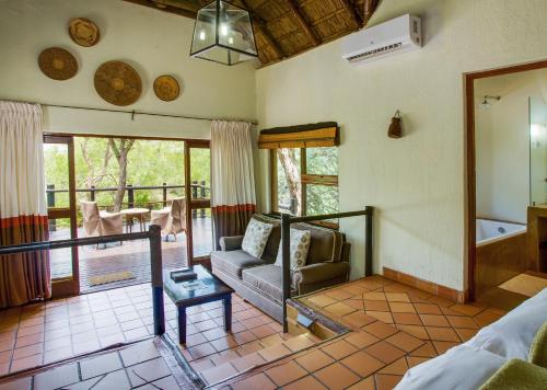 Madikwe River Lodge by Dream Resorts في محميّة ماديكوي الطبيعيّة للطرائد: غرفة معيشة مع أريكة وشرفة