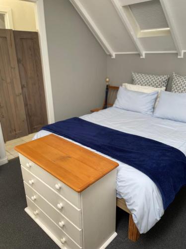 a bedroom with a white bed with a wooden dresser at Beside Still Waters in Wilderness