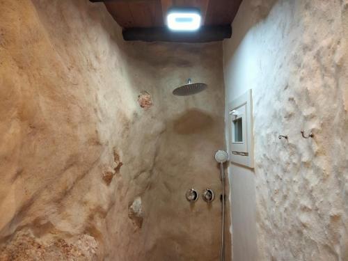 a bathroom with a shower in a stone wall at Casa Cueva El Naranjo Rocabella in El Chorro