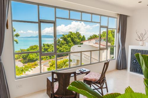 a room with a large window with a view of the ocean at Ampersand Resort in Bophut 