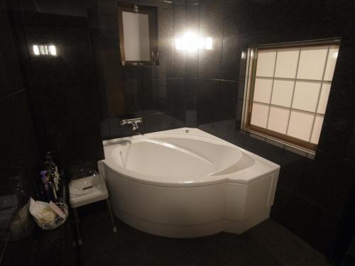 una vasca bianca in un bagno con finestra di ホテルラパンセ Adult Only a Saitama