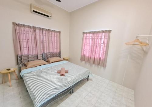 a bedroom with a bed with pink curtains and a pink toy at Air-home No 9 Kampung Boyan, 4BR, 9pax, Netflix in Taiping
