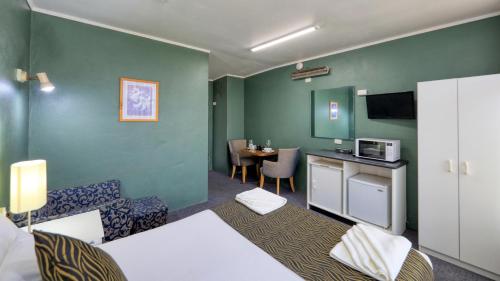 a room with a bed and a table with a microwave at Silver Oaks Motel in Gilgandra