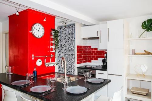 une cuisine avec un mur rouge et une horloge murale dans l'établissement Le Duomo - Duplex avec vue sur le Dôme de la Grave, à Toulouse