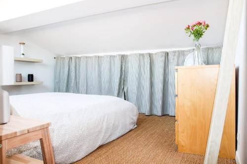 - une chambre avec un lit blanc et un vase de fleurs sur une armoire dans l'établissement Le Duomo - Duplex avec vue sur le Dôme de la Grave, à Toulouse