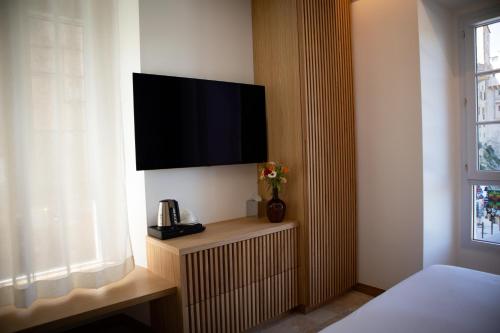 a hotel room with a television on a wall at Le Royal Hôtel Restaurant in Bonifacio