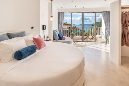 ein weißes Bett in einem Zimmer mit Meerblick in der Unterkunft Ampersand Resort in Bophut 