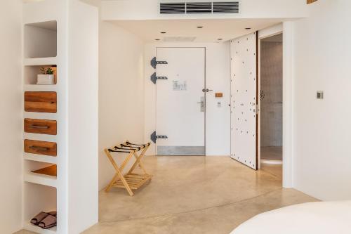 a room with white walls and a hallway with a chair at Ampersand Resort in Bophut 