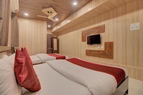 a bedroom with two beds and a flat screen tv at Hotel Snehaprabha - Near to Nagaon Beach Alibaug in Alibaug