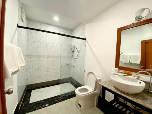 a bathroom with a toilet and a sink and a mirror at Nakasang Paradise Hotel in Nakasong
