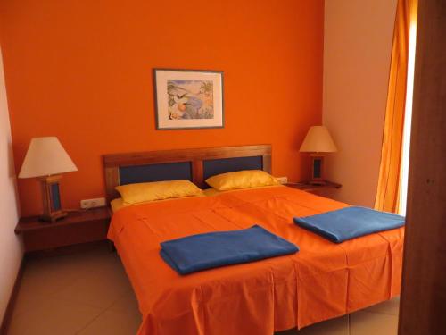 a bedroom with a bed with two blue pillows on it at Bungalow Marietta in Vila do Maio