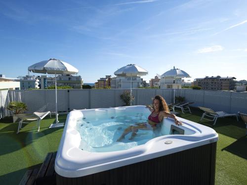 a woman sitting in a hot tub on a roof at Hotel Pillon in Bibione