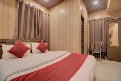a bedroom with a large bed with red pillows at Hotel Snehaprabha - Near to Nagaon Beach Alibaug in Alibaug