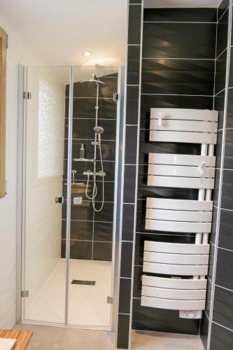a glass shower in a bathroom with black tiles at Homgaïa chambres d'hôtes in Clisson