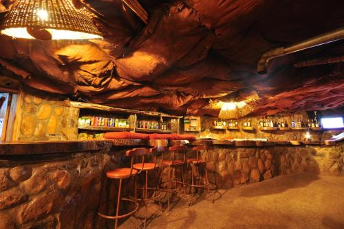 a bar with stools in a room with a rock wall at Naiberi River Campsite & Resort in Eldoret
