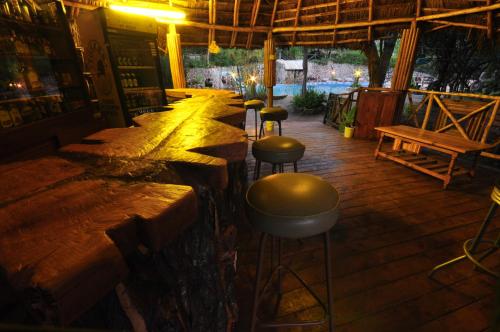 a bar with stools and a row of tables and benches at Naiberi River Campsite & Resort in Eldoret