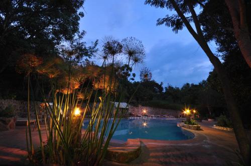 ein Pool mit Bäumen und Lichtern in der Nacht in der Unterkunft Naiberi River Campsite & Resort in Eldoret