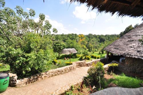 a view of a garden with a thatch roof at Naiberi River Campsite & Resort in Eldoret
