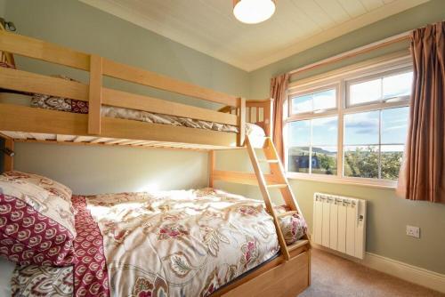 a bedroom with two bunk beds and a window at Rose Cottage Elsdon in Elsdon
