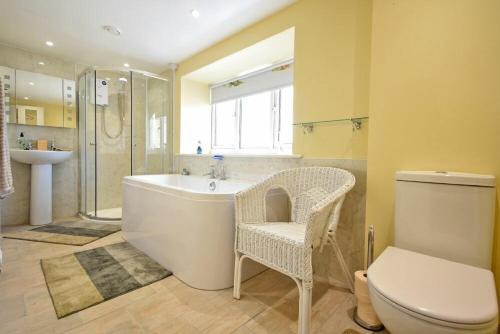 a bathroom with a tub and a toilet and a sink at The Lodge Elsdon in Elsdon