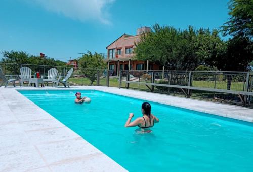 two children swimming in a swimming pool at Cabañas Y Departamentos Bettylu in Villa Cura Brochero
