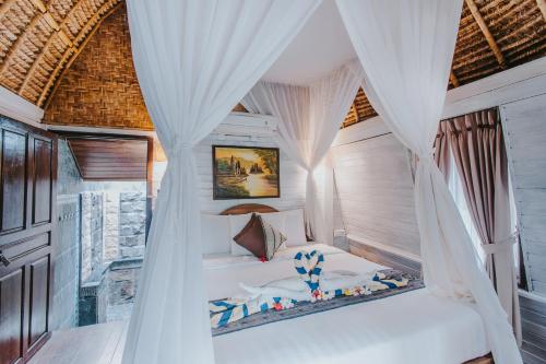 Ce lit se trouve dans un dortoir doté de rideaux blancs. dans l'établissement Alam Nusa Bungalow Huts & Spa, à Nusa Lembongan