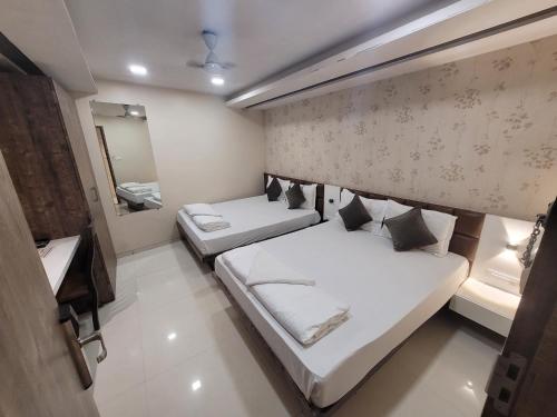 een kleine kamer met 2 bedden en een spiegel bij Hotel Heritage - Near Trade Center, Visa Consulate BKC in Mumbai