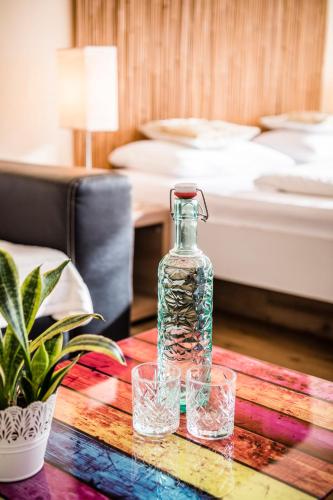 a glass bottle and two glasses on a table in a room at Hotel Bamboo in Coldrano