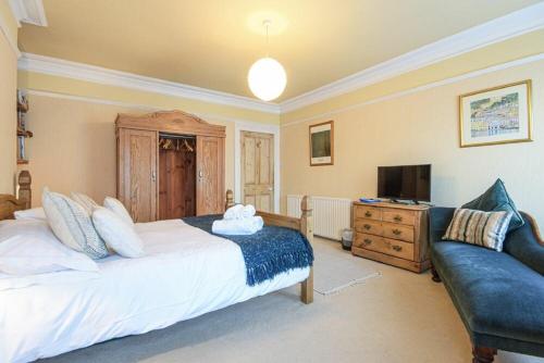 a bedroom with a bed and a couch and a television at The Burgage House in Warkworth