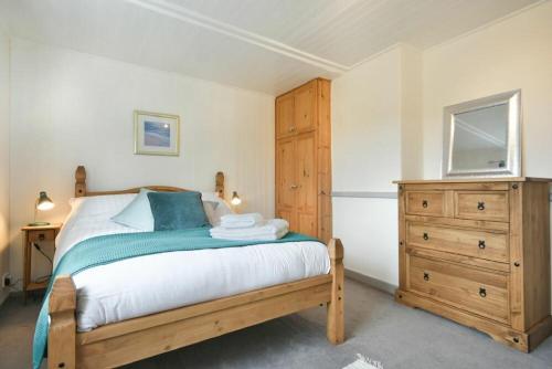 a bedroom with a bed with a wooden dresser and a drawer at The Burgage House in Warkworth