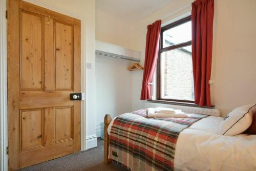 a bedroom with a bed and a window with red curtains at The Burgage House in Warkworth