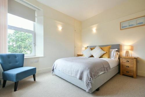 1 dormitorio con 1 cama y 1 silla azul en St Julians, en Alnmouth