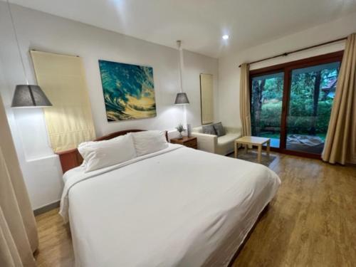 een slaapkamer met een groot wit bed en een raam bij Samui Garden Home - SHA Extra Plus in Lamai