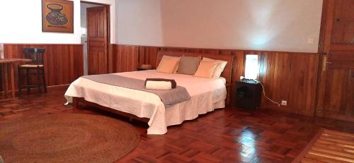 a bedroom with a large bed in a room with wooden floors at L'anis Etoilé - Hôtel Restaurant in Antsirabe