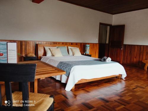 a bedroom with a large bed and a wooden floor at L'anis Etoilé - Hôtel Restaurant in Antsirabe
