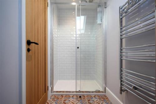 a shower with a glass door in a bathroom at Marmalade Cottage in Seahouses