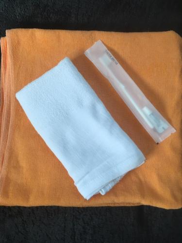 a pair of white towels sitting on a orange towel at Lodge Shosen in Otari