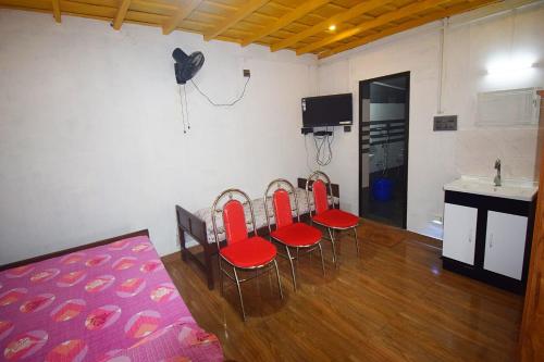 a room with four red chairs and a kitchen at Munroe Inn Homestay in Kollam