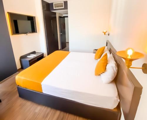 a bedroom with a bed with yellow pillows and a tv at Hotel Güleryüz 2 in Antalya