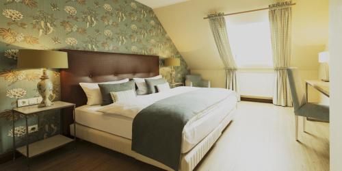 a bedroom with a large bed and a wall with floral wallpaper at Weingut Hees - Landgasthof Zum Jäger aus Kurpfalz in Auen