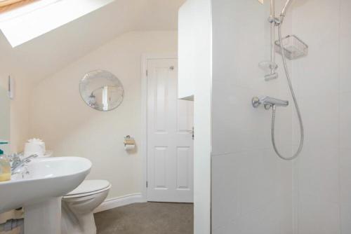 a white bathroom with a sink and a shower at The Old Concert Room in Alnmouth