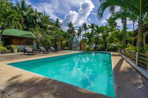 a swimming pool in a resort with palm trees at Charisma Beach Resort in Siquijor