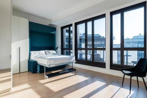 Schlafzimmer mit einem Bett, einem Stuhl und Fenstern in der Unterkunft easyhomes-Central Tower in Mailand