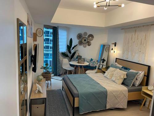 a bedroom with a bed and a living room with a table at Cozy Studio Unit at Azure North San Fernando Pampanga in San Fernando