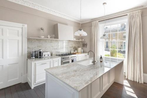 a white kitchen with a large marble counter top at Dunsford House - Elegant Townhouse with Parking in Bath